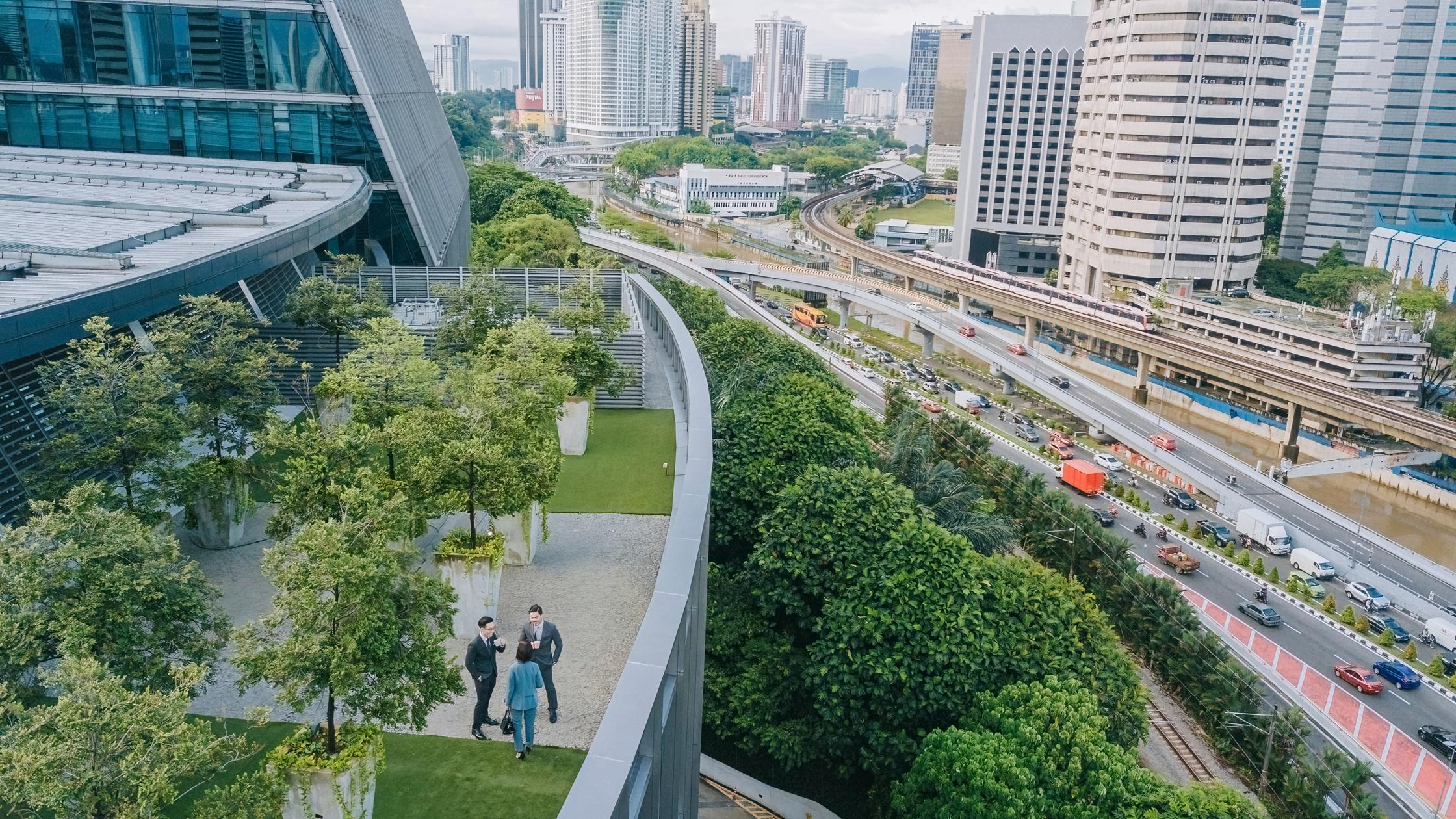 Directly above 3 business people talking on roof top garden outside office building.