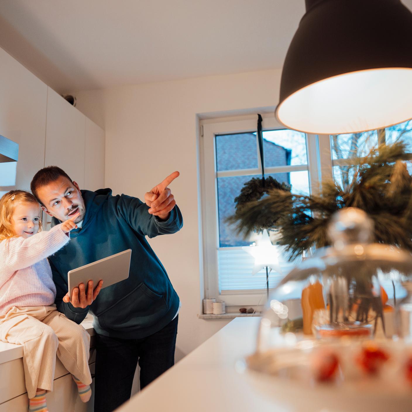 Künstliche Intelligenz – Vater und Tochter zeigen in der Küche aufeinander